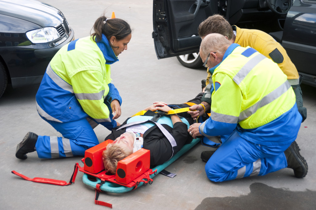 Paramedics and a fireman strapping a wounded woman with a neck brace on a stretcher